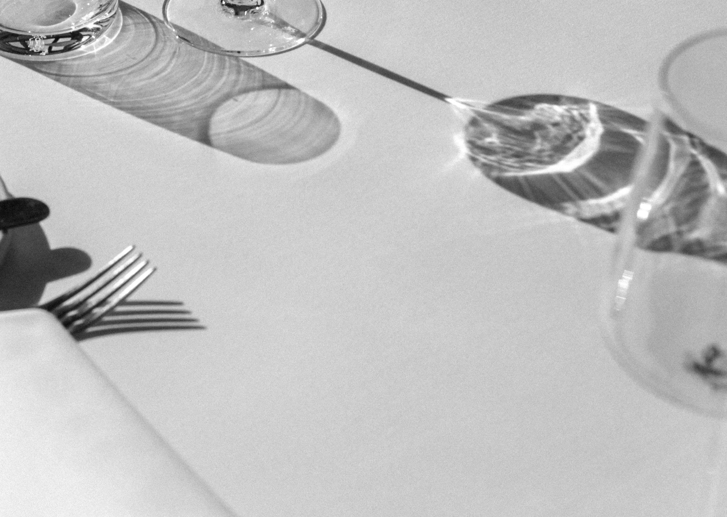 Une table dressée : nappe blanche, verres et couverts dans la lumière.